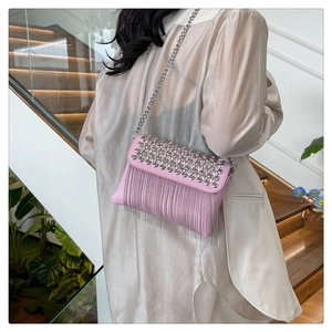 Close-up of pink crossbody bag featuring silver studs and long metal fringe tassels