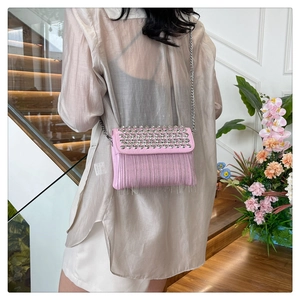Close-up of pink crossbody bag featuring silver stud rivets and long metal chain tassels