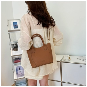 Sac à main en cuir marron grainé porté à l'épaule pour montrer le volume et le style