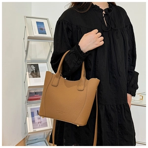 Vue détaillée du sac seau marron en cuir texturé litchi avec pieds de protection dorés
