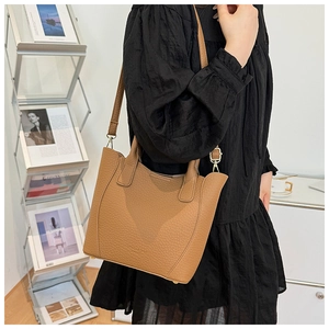 Détail d'un sac seau en cuir grainé marron avec poignées et pieds de protection en métal