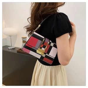 Detail of color-block plaid handbag with gold square buckle and chain strap on a shoulder