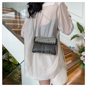 Detailed view of black crossbody bag with sparkling rhinestones and silver chain tassels