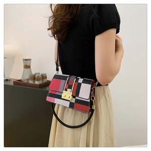Detail of color-block geometric pattern square bag with gold lock and round handle