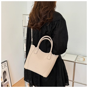 Gros plan détaillé du sac seau en cuir grainé crème avec pieds de protection