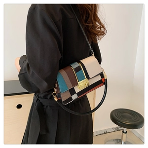 Detail of color-block crossbody bag with gold square lock worn over a black dress