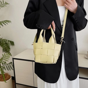 Mini sac à main chic en cuir tressé beige avec bandoulière porté par un mannequin