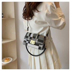 Close-up of a plaid shoulder bag with a gold lock, displayed in a minimal lifestyle setting