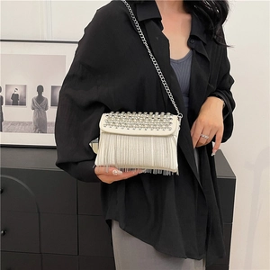 White rhinestone crossbody bag with fringe chain tassels worn by a model in black shirt
