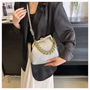 Detail of silver shell bag with lychee texture, golden chain handle and metal clasp