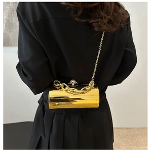 Goldene zylindrische Abendtasche aus Acryl mit Perlenverschluss und Kettenriemen am Modell
