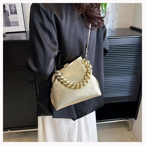 Detail of gold metallic chain handle and textured leather on a luxury evening clutch