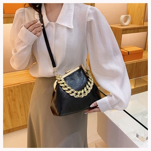 Detailed view of black lychee grain leather shell bag with thick gold chain handle and strap