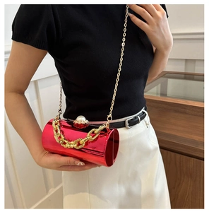 Detail der roten zylindrischen Acryl-Clutch mit goldener Kette und Perlenverschluss