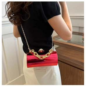 Nahaufnahme der roten zylindrischen Acryl-Tasche mit goldener Kette und Perlenverschluss