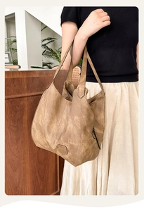 Close-up of vintage brown leather tote bag with embossed logo and side zipper detail