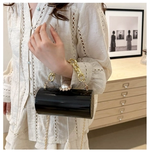 Detail der schwarzen zylindrischen Clutch mit Perlenverschluss und Goldkette
