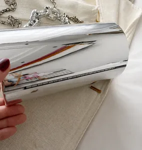Nahaufnahme einer silbernen Spiegel-Zylindertasche mit einer klobigen Metallkette