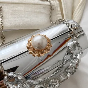 Detail der silbernen Abendtasche mit Perlenverschluss und goldenen Blumenakzenten