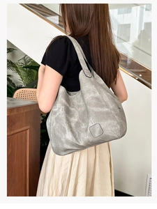 Detail of silver tote bag showing its metallic texture and stylish pleated design