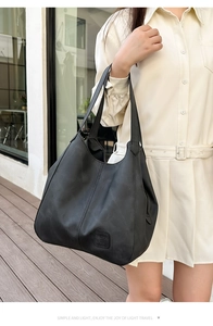 Detail view of large black leather shoulder bag with textured surface and fine stitching