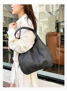 Close-up of soft black leather tote bag featuring a textured finish and embossed leather tag