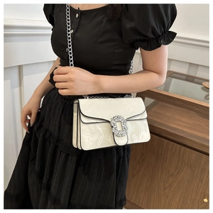 Detail of white marble print crossbody bag with rhinestone buckle and silver chain strap
