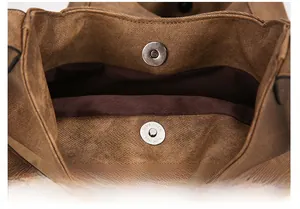Detail of vintage brown canvas bag featuring dual silver magnetic snap closures
