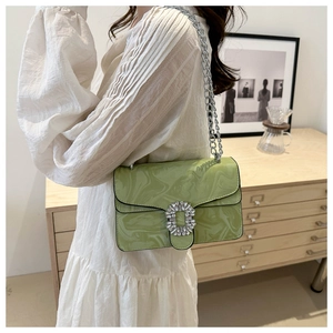 Detail of light green marble-textured crossbody bag with crystal buckle and silver chain