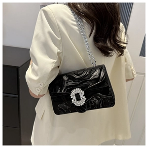 Detail of black marble textured shoulder bag featuring a sparkling rhinestone buckle
