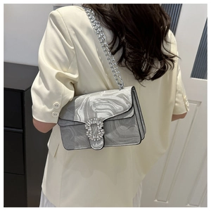 Detail of silver marble patterned crossbody bag with rhinestone buckle on model side