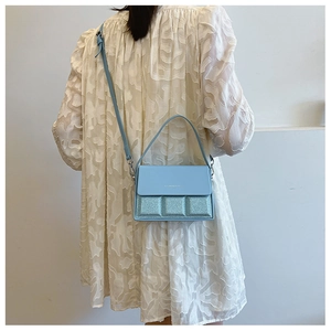 Rear view of a model wearing a light blue sequined crossbody bag with a floral dress