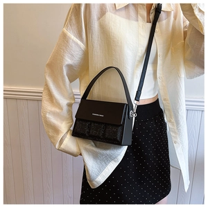 Detail of fashion crossbody bag featuring black sequins and white letter logo engraving