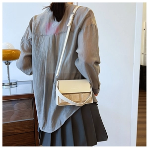 Detail of white leather and gold fabric crossbody bag with adjustable strap and metal buckle