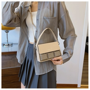 Detail of beige shoulder bag with gold sequin base and fashion text on the flap