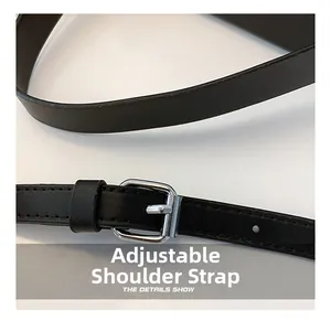 Detail showing the adjustable black leather shoulder strap with a silver metal buckle