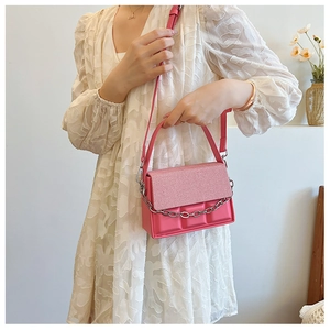 Detail of pink chocolate pattern crossbody bag with silver chain on lace dress