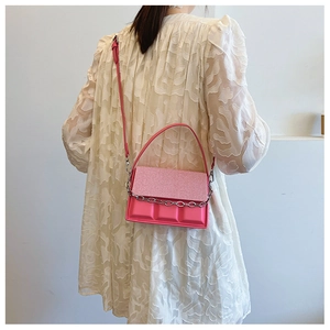 Detail of bright pink box bag with 3D texture and silver chain on white dress