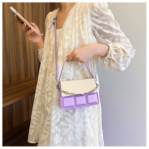Detail of two-tone crossbody bag with chocolate pattern texture and silver chain strap