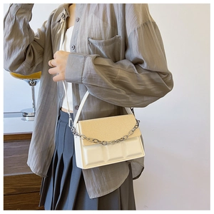 Close-up of stylish white crossbody bag with woven texture and silver chain detail