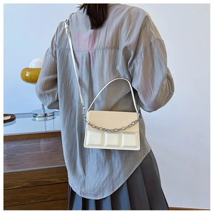 Detail view of white PU leather crossbody bag with geometric texture and silver chain