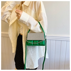 Detailed shot of a green crossbody box bag with silver textured flap on a female model