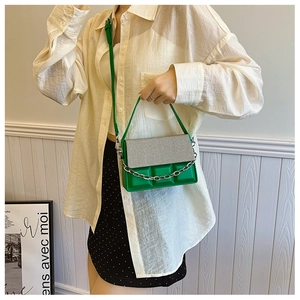 Detail of green crossbody bag with silver textured flap and 3D chocolate block design