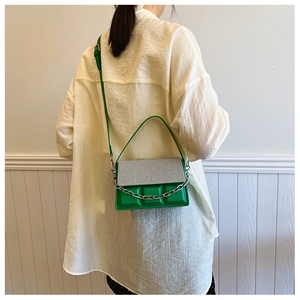 Detail of green checkered box bag with silver chain and weave pattern texture