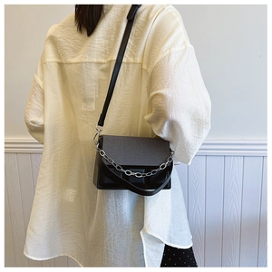Detail of black crossbody box bag with textured fabric and geometric pattern finish