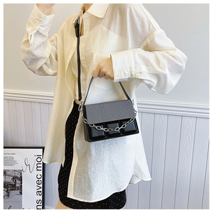 Close-up of elegant black leather handbag with silver chain and tweed texture detail