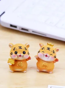 Nahaufnahme von süßen Glückstiger-Figuren mit Symbolen auf einem Schreibtisch mit Laptop