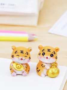 Nahaufnahme süßer Tigerfiguren aus Harz mit Goldbarren und Geldsack auf dem Tisch