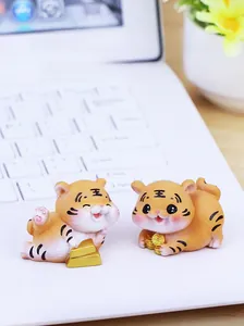 Detail von zwei süßen Harz-Tigerfiguren mit Goldmünzen auf einer weißen Laptoptastatur