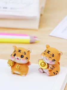 Detailansicht süßer Tigerfiguren aus Harz mit Goldbarren auf einem gemütlichen Schreibtisch